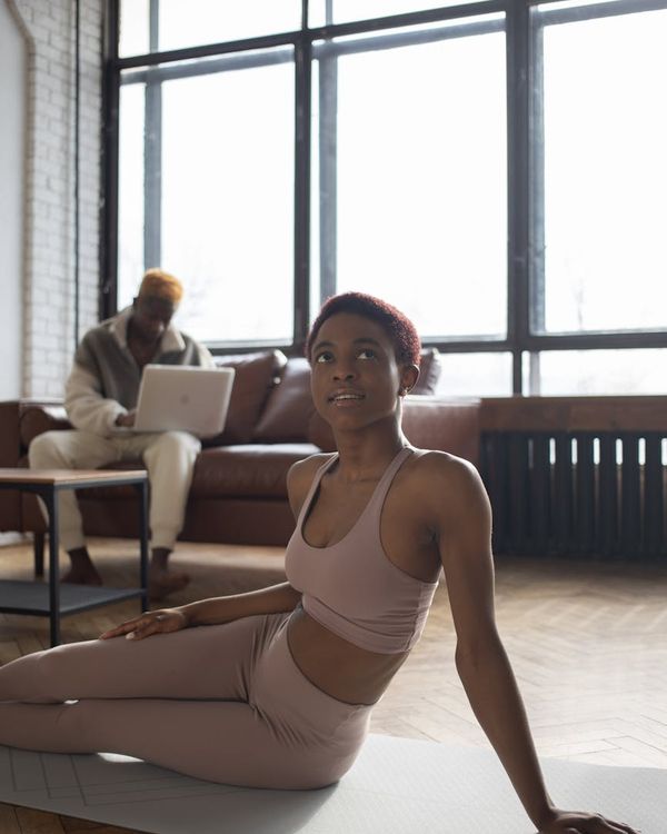 A woman in comfortable sportswear stretching gently in a bright room.